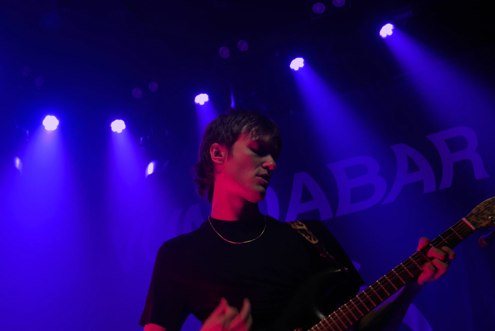 Vundabar's Brandon playing guitar with red light in his face and purple light in the background